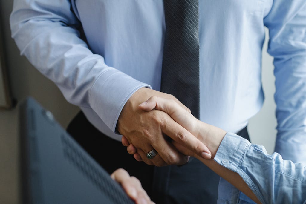 High angle of crop unrecognizable male and female business partners in formal clothes shaking hands after successful deal